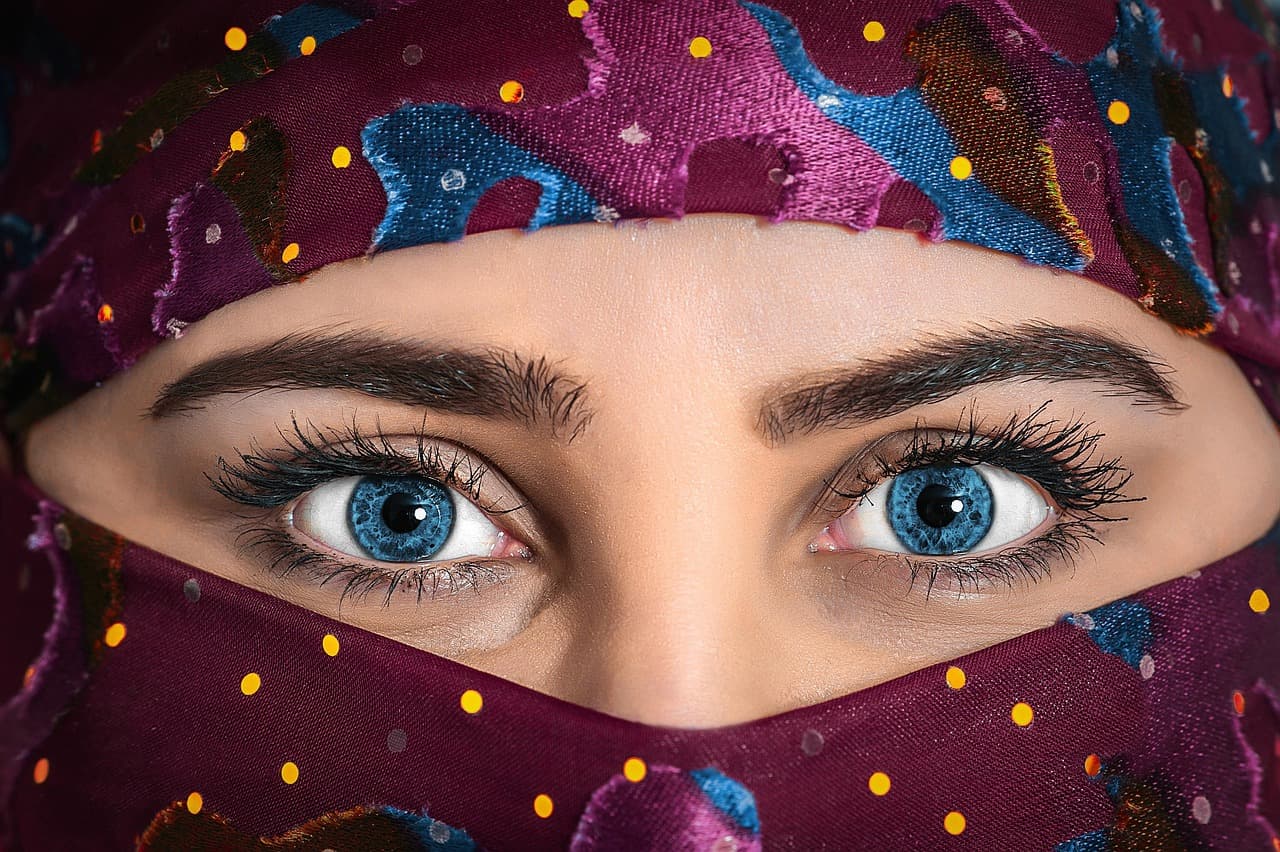 Full, defined brows above two eyes, the face framed by a patterned scarf