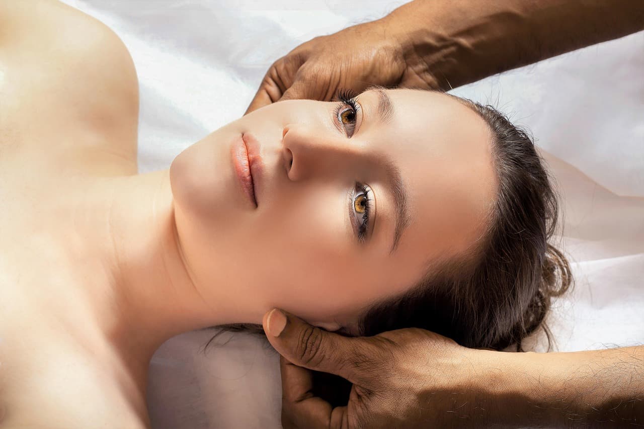 A therapist’s hands massaging a client’s head and temples