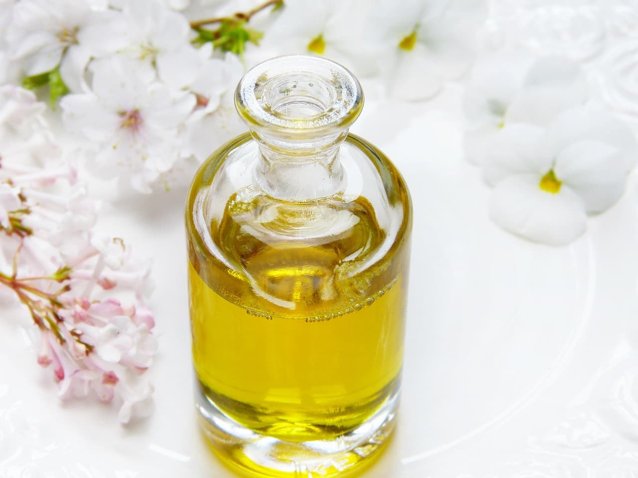 A glass bottle of oil among white blossom
